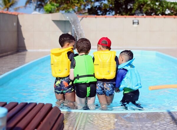 a group of young boys standing next to a swimming pool