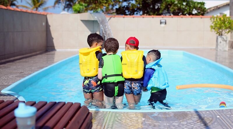 a group of young boys standing next to a swimming pool