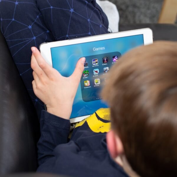 a young boy sitting on a couch holding a tablet