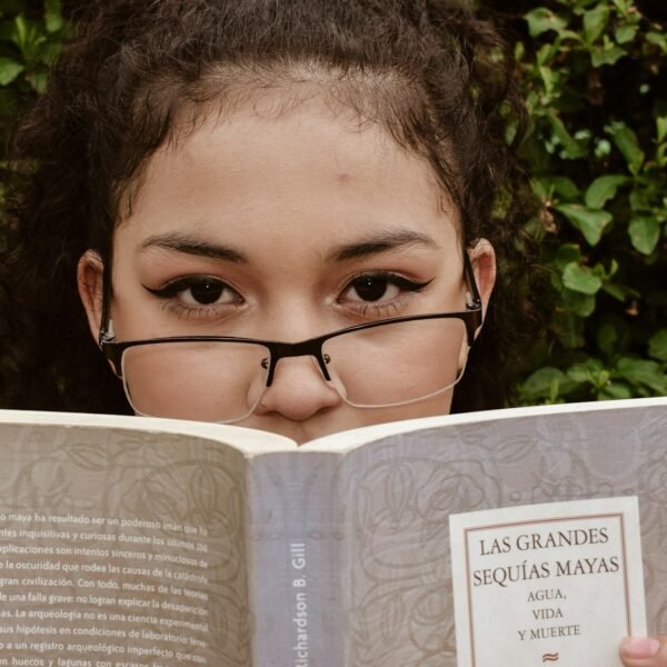 A young girl wearing glasses reading a book