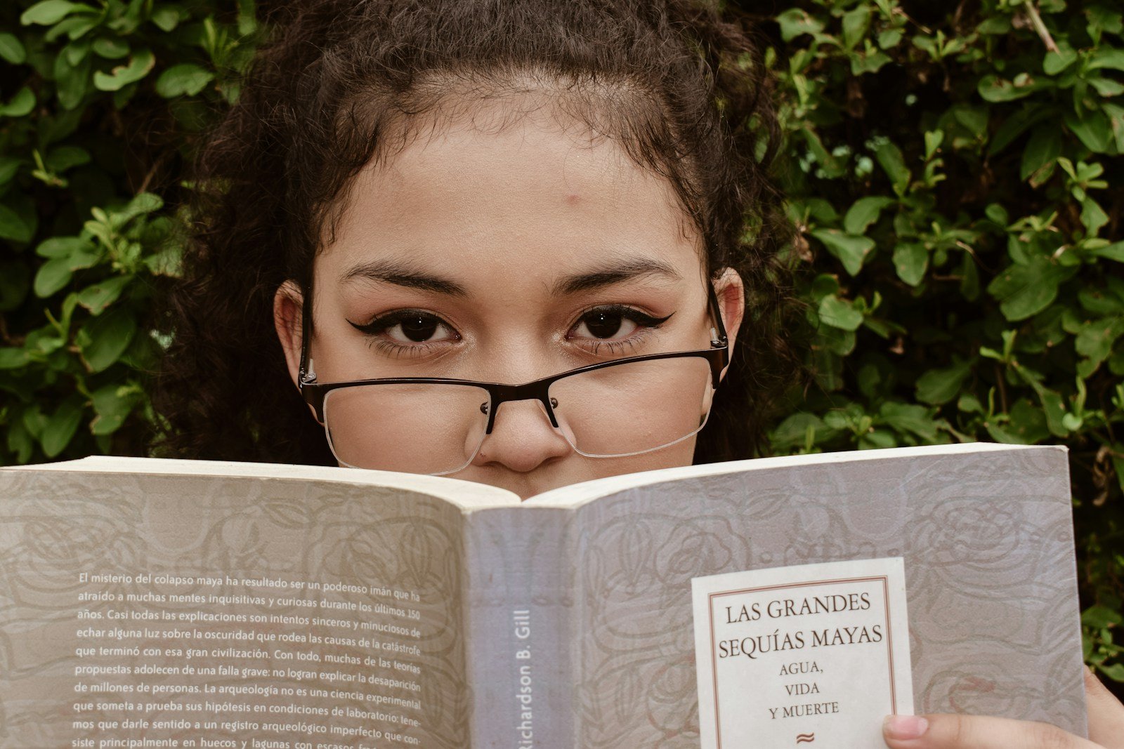 A young girl wearing glasses reading a book